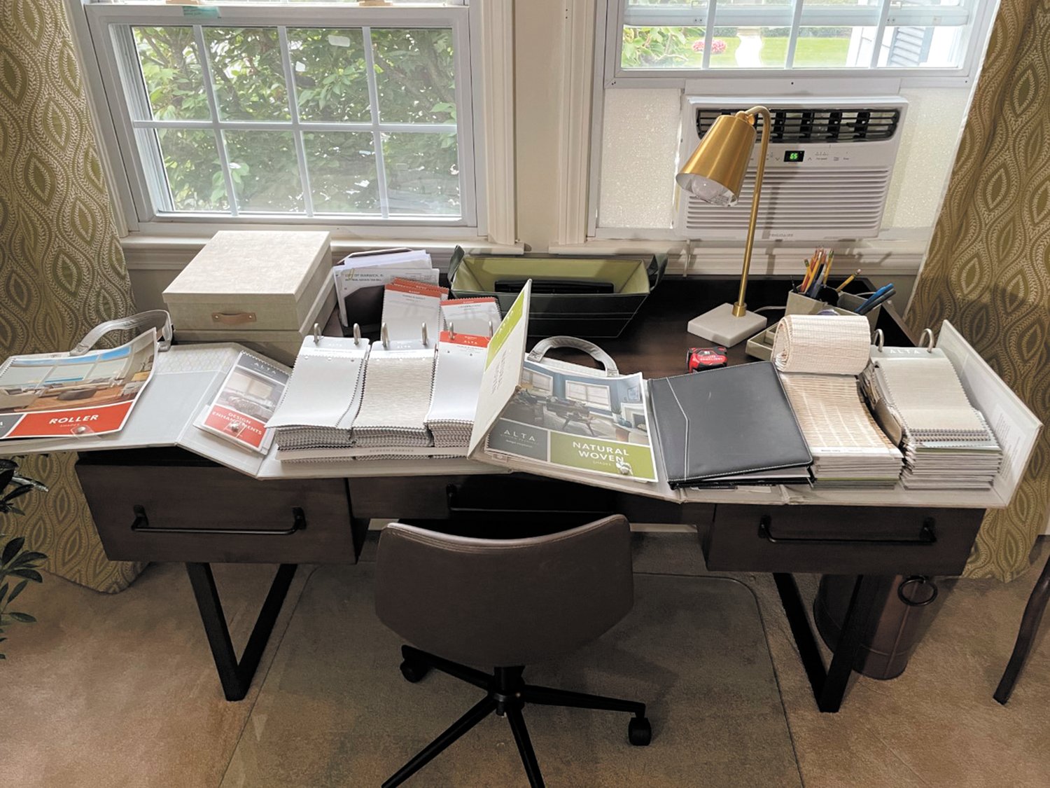 Piles of samples cover the desk of Warwick resident Jennifer Jones as she checks out the many shade options from Harris Blinds & Shutters. This is her free consultation!
